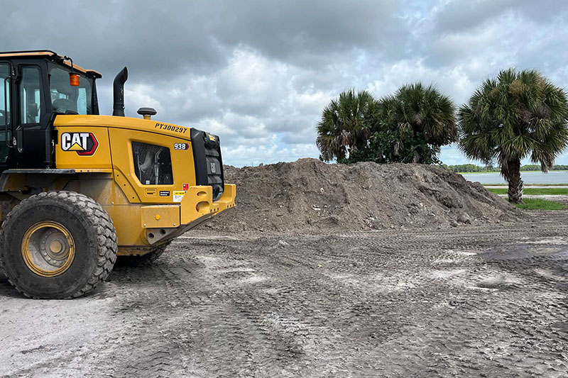 Bulldozer backfilling lot next to large load of fill dirt near Vero Beach, FL