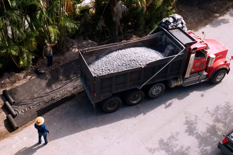 Dump truck delivering bulk #57 stone to landscape project site in St. Petersburg, Florida