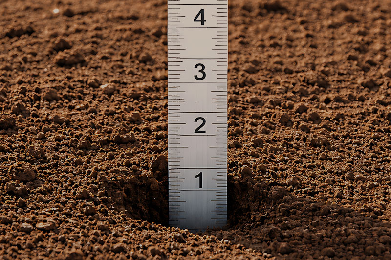 ruler measuring topsoil depth in garden